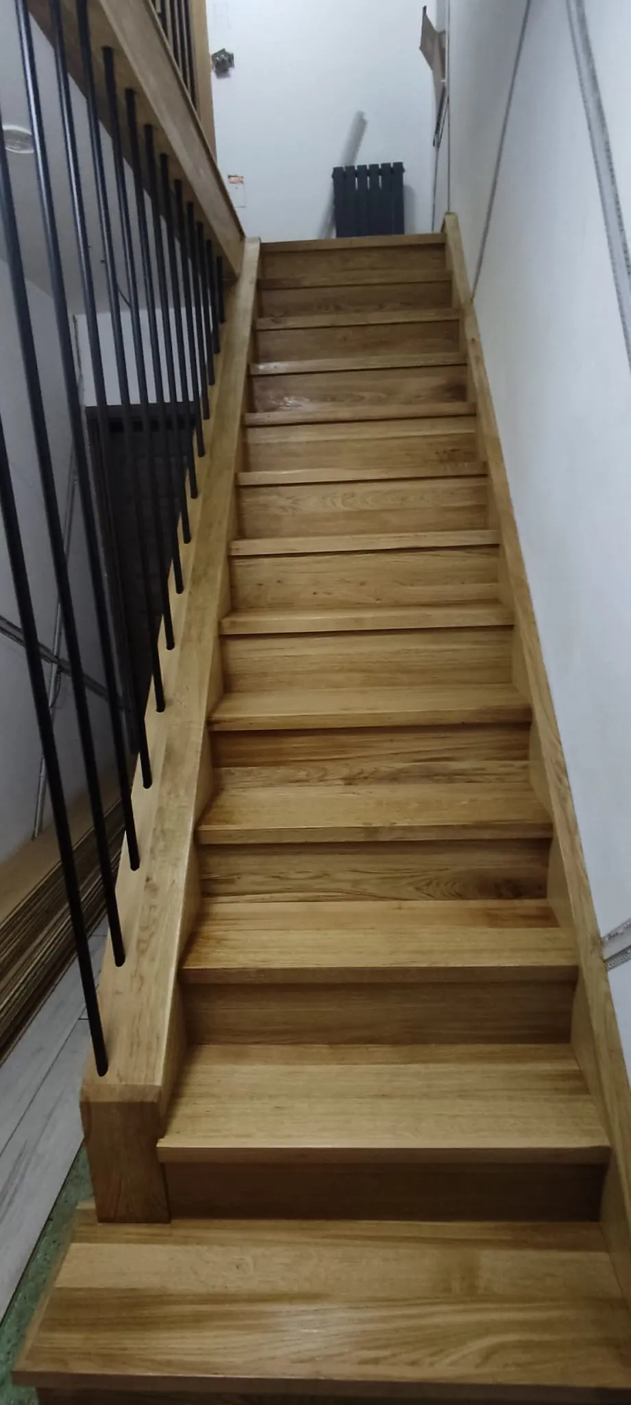 Straight timber staircase seen from the front with black vertical balusters on the left
