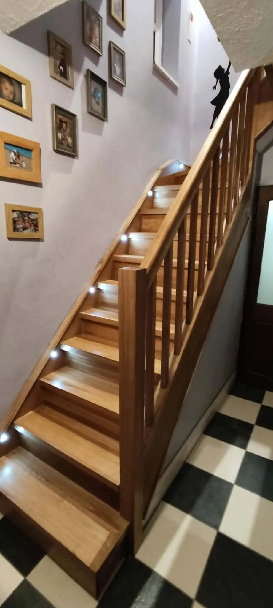 Timber staircase with turned spindles and a handrail, above a black and white tiled hall floor