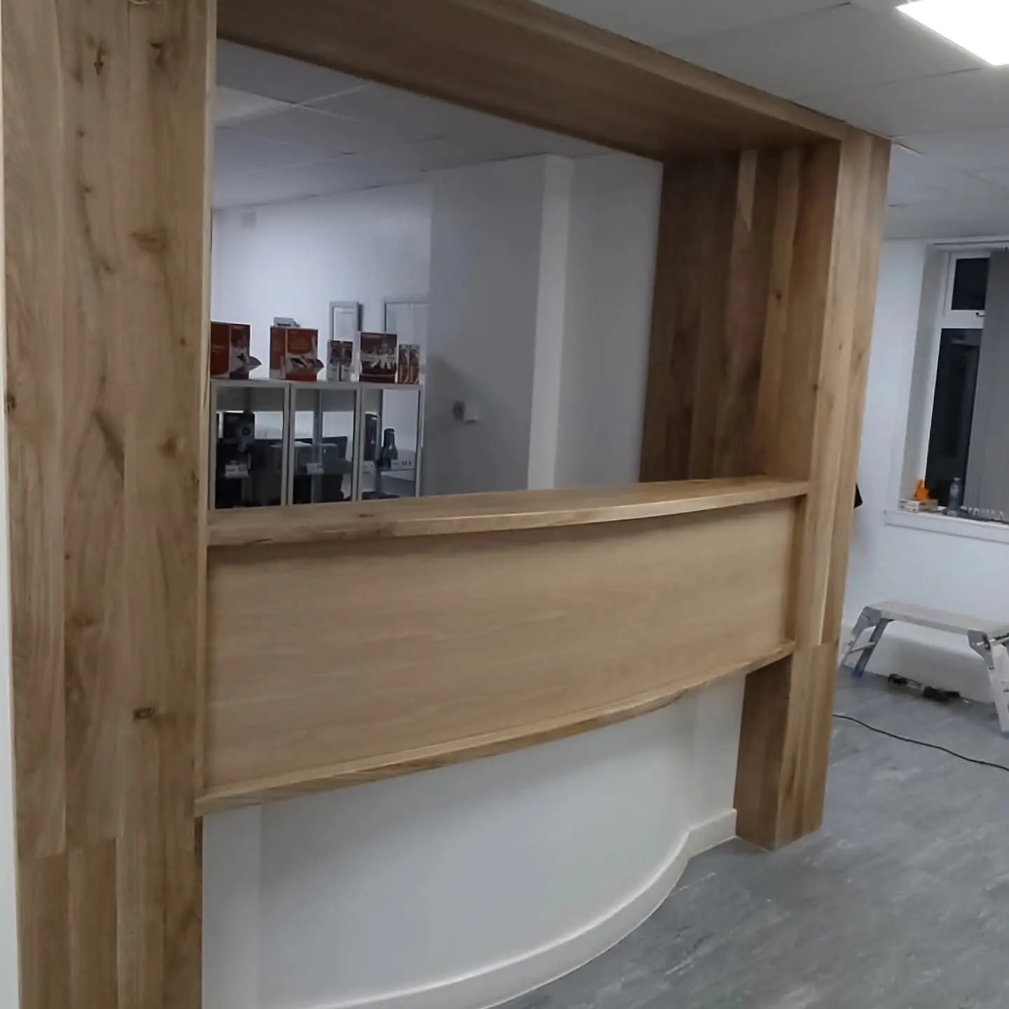 Timber-framed interior opening with a curved timber counter-height panel beneath it, in a bright room